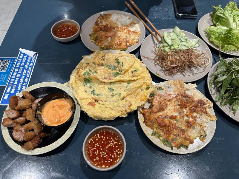 Một bàn bánh ép nhiều loại nhân, thịt nướng và nước chấm